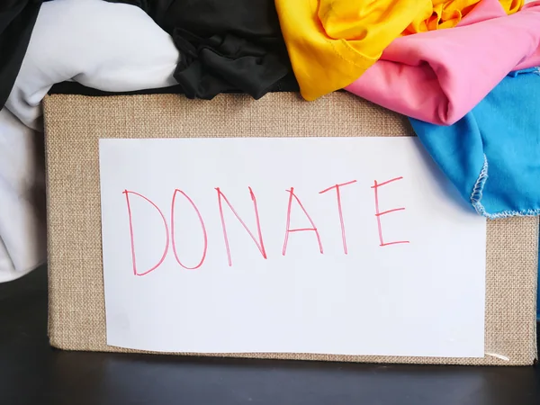 A box of clothing marked for donation during a household cleanout or downsizing project