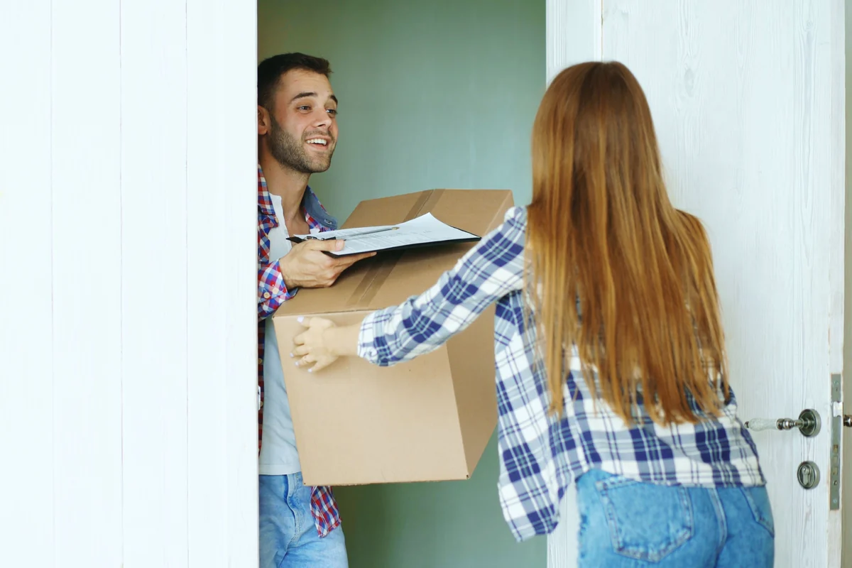 People carrying a moving box through a doorway during a residential transition